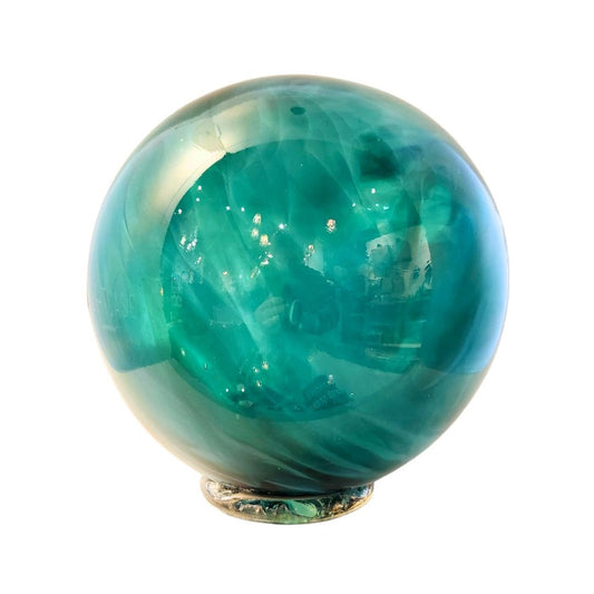 teal glass float, sphere, shiny, has small glass foot at bottom, foot is similar in shape and size to a cookie, makes float free standing.